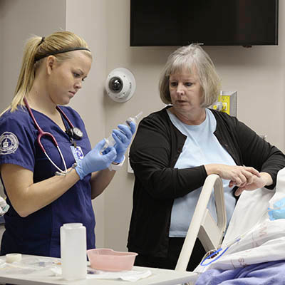 A nursing student prepares a syringe to administer medicine by IV.